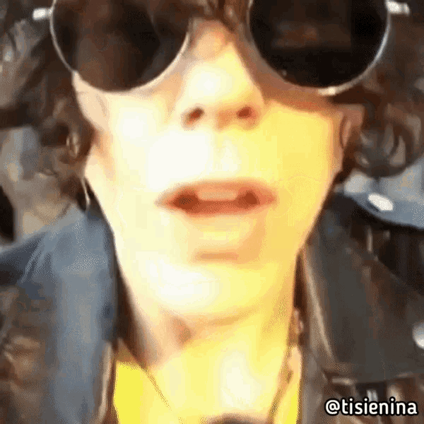a close up of a person wearing sunglasses and a yellow shirt .