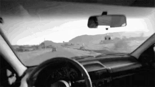 a black and white photo of a person driving a car on a highway .