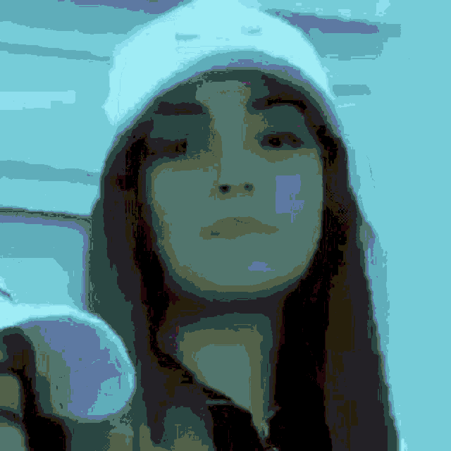 a close up of a woman wearing a white hat and a hoodie .