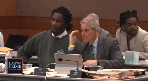 a man sits at a table with a sign that says law crime