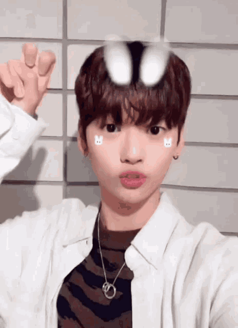 a young man wearing a white shirt and a necklace has bunny stickers on his face