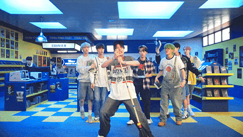 a group of young men are dancing in a store with a sign that says ' empty video club ' on it
