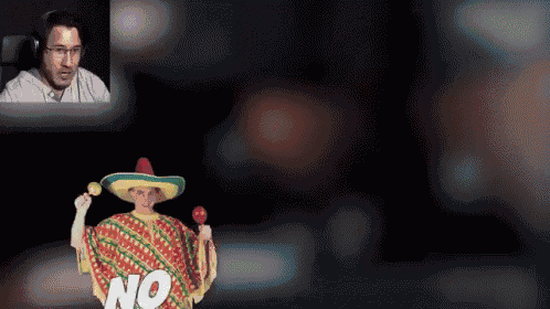 a man wearing a sombrero and a poncho holds maracas and says no