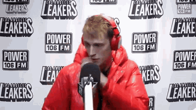 a man in a red jacket is standing in front of a wall that says power 106 fm