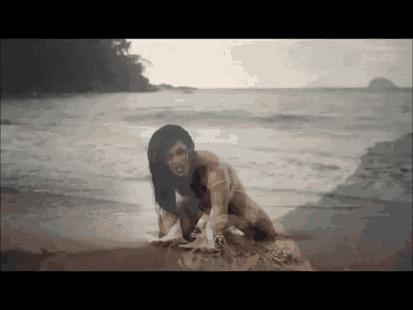 a woman in a bikini is crawling on the beach near the ocean