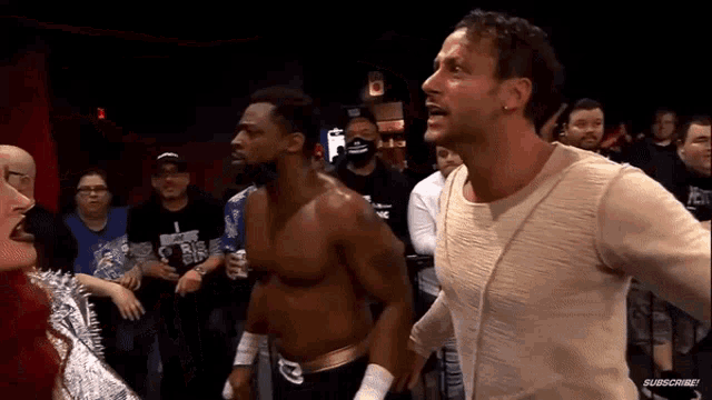 a man in a white shirt is standing next to a man in a black shirt in a crowd .