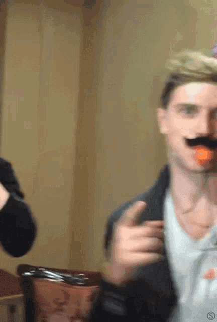 a man wearing a fake mustache is holding an orange in his mouth ..