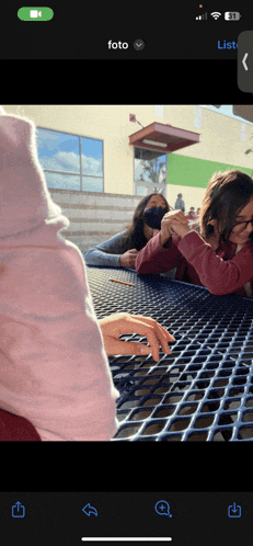 a phone screen shows a group of people sitting at a table and a green button that says foto