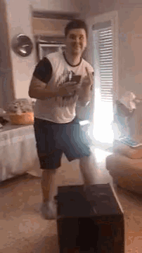 a man is standing on a box in a living room while holding a remote control .