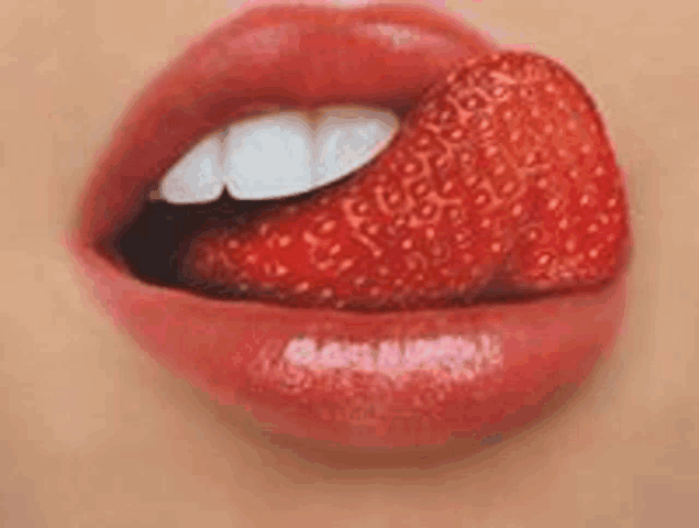 a woman is licking a strawberry from her lips .