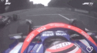 a man is driving a red bull race car on a track