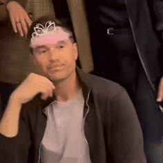 a man wearing a tiara on his head is sitting down
