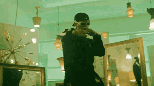 a man wearing sunglasses and a hat stands in front of mirrors