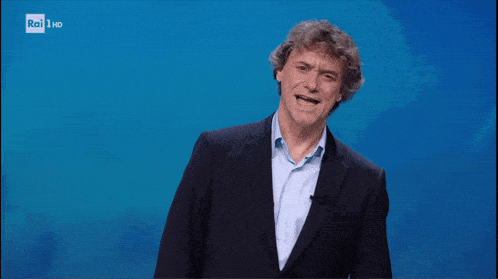 a man in a suit stands in front of a rai hd screen