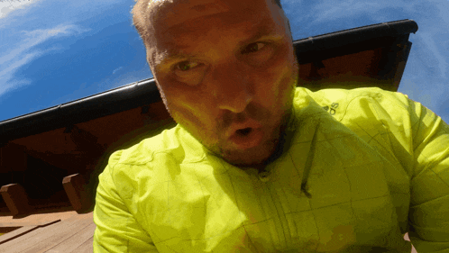 a man wearing a neon yellow adidas jacket looks surprised