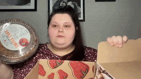 a woman is holding a pie and a box of coffee cake
