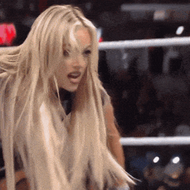 a woman with blonde hair is standing in a ring with her mouth open