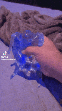 a person is holding a bag of ice in their hand in front of a bed .