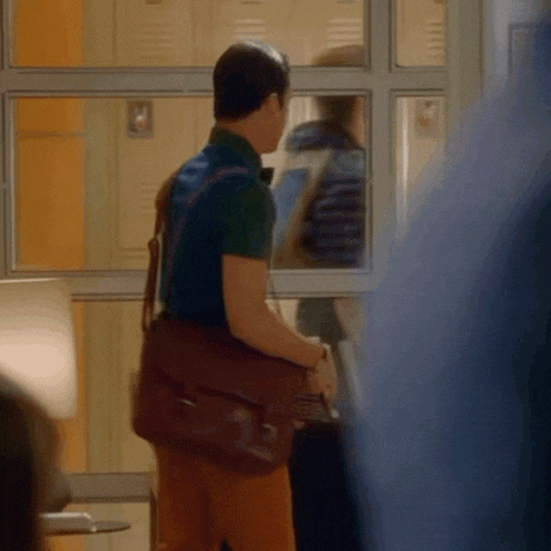 a man in a green shirt is carrying a brown leather bag
