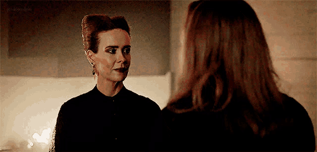two women are standing next to each other and talking to each other