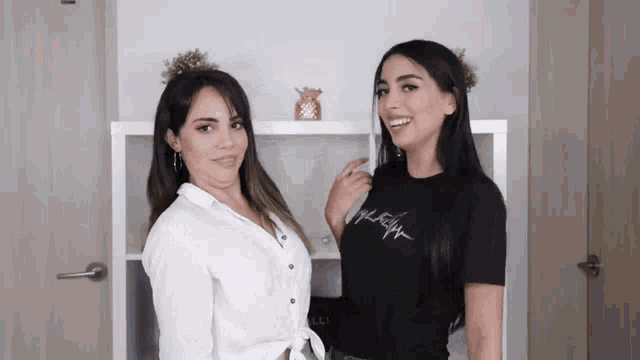 two women standing next to each other with one wearing a black shirt that says ' tommy hilfiger '