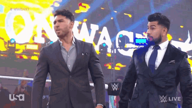two men in suits are standing in front of a sign that says owen