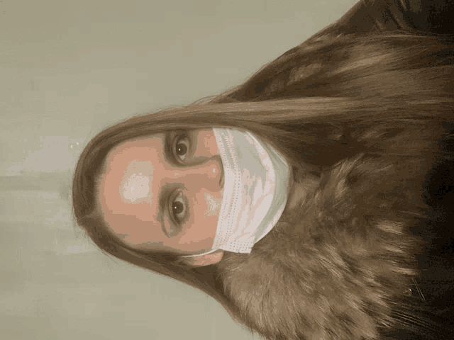 a woman wearing a face mask and a fur collar