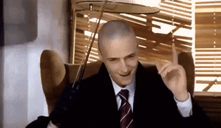 a man in a suit and tie is sitting in a chair and smiling