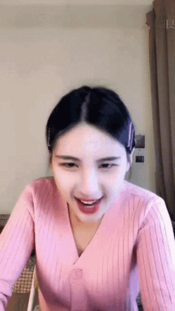 a woman wearing a pink sweater is smiling and looking at the camera