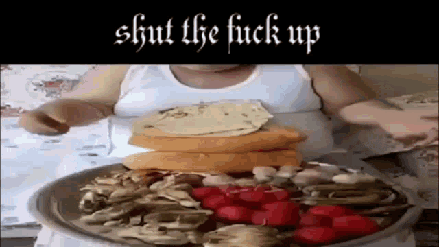 a man is sitting at a table with a plate of food with the words shut the fuck up above him