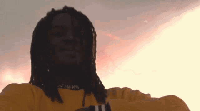 a man with dreadlocks is wearing a yellow shirt that says nike