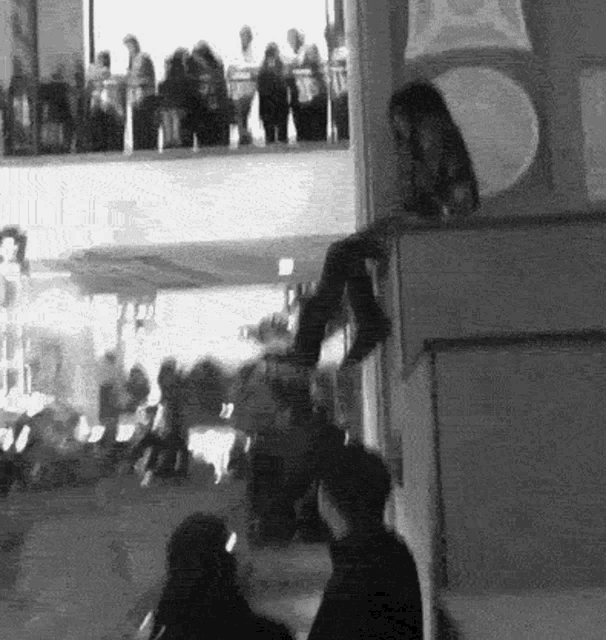 a black and white photo of a group of people sitting on a ledge .