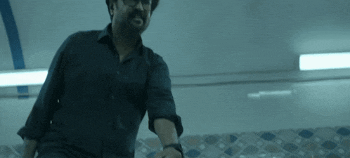 a man in a black shirt and glasses is standing in front of a tiled wall