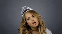 a woman wearing a tiara says " i 'm a princess " with her finger