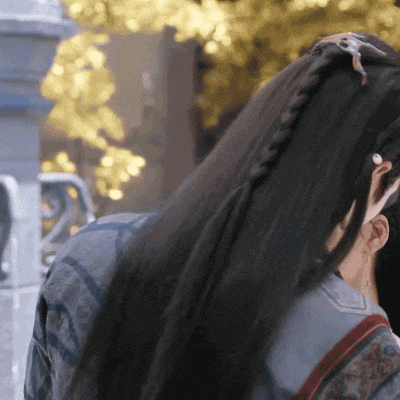 a woman with long black hair is wearing a braided ponytail .