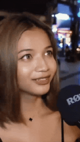 a woman is talking into a microphone while wearing a black top .