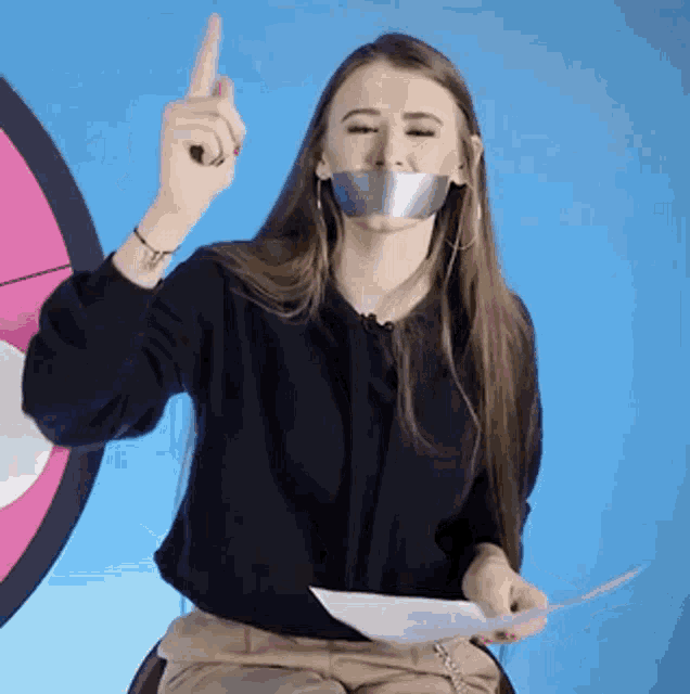 a woman with duct tape over her mouth is holding a piece of paper