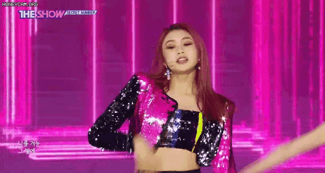 a woman is dancing on a stage in front of a pink background .