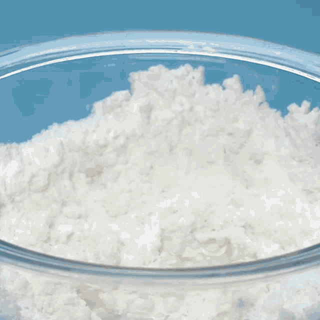 a person is whisking a bowl of flour with a whisk