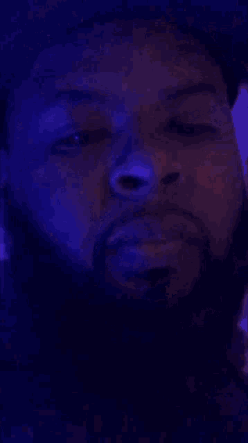 a close up of a man 's face in a dark room with blue lights behind him