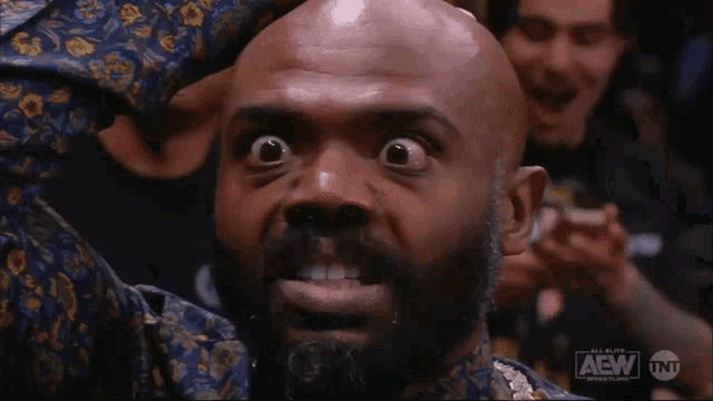 a bald man with a beard is making a funny face while watching a wrestling show