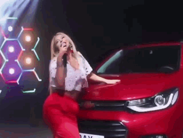 a woman is standing in front of a red car with a license plate that says day