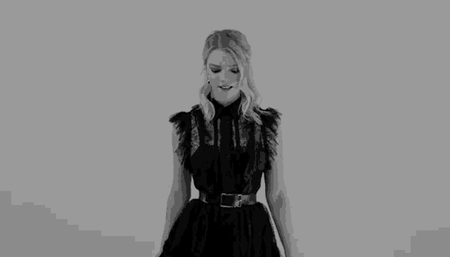 a woman in a black dress is dancing with her arms outstretched .