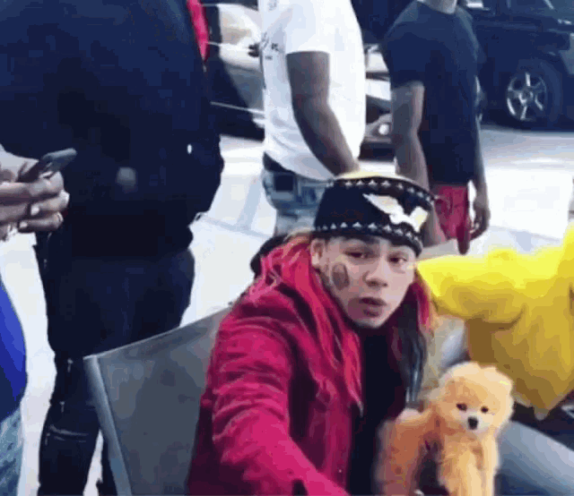 a man in a red jacket is sitting in a chair holding a teddy bear .