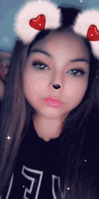 a girl wearing a furry headband with hearts on it looks at the camera