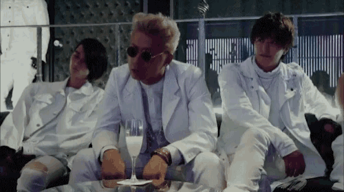 a man in a white suit sits with two other men
