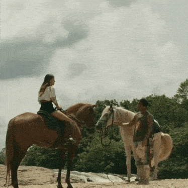 a woman riding a horse next to a man standing next to a horse