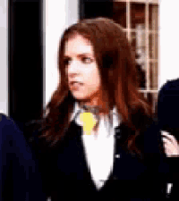 a woman in a suit and tie is standing in front of a window .