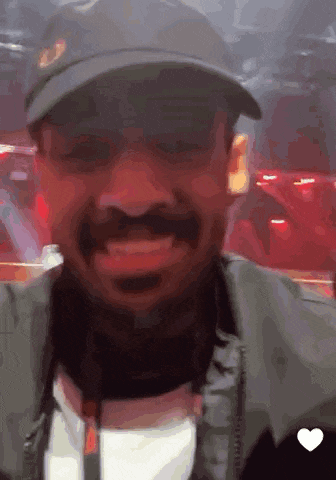 a man wearing a hat and jacket is smiling with a heart in the corner