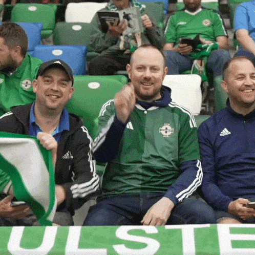 a group of men are sitting in a stadium holding a green banner that says ulste